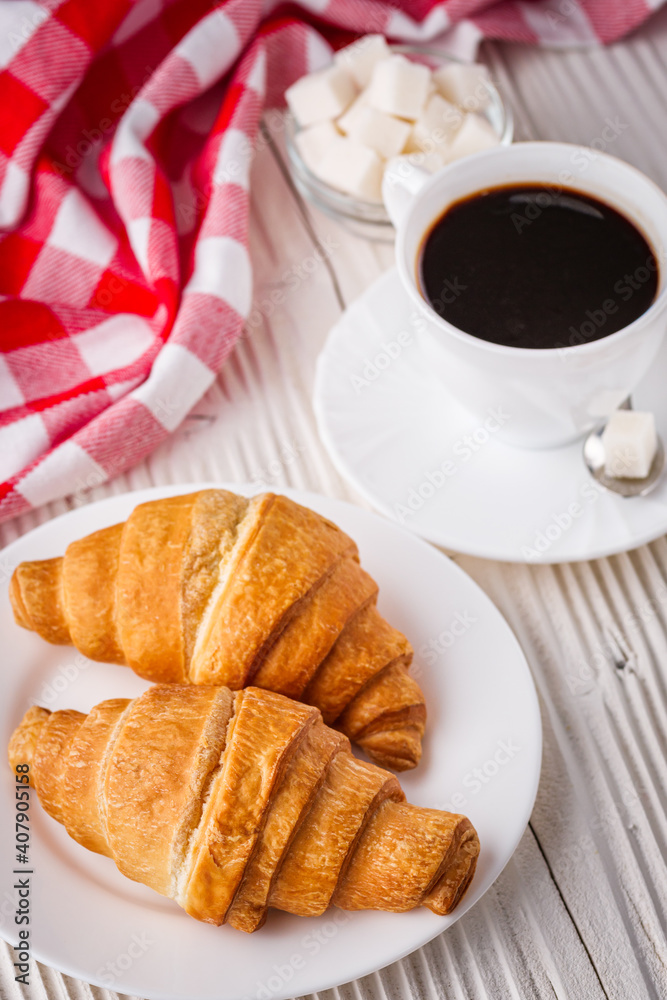 delicious fresh croissant and cup of coffee on a white wooden rustic background