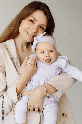 Portrait of beautiful woman with cute newborn baby girl in studio. Loving mother hold adorable little daughter in arms, enjoy happy moments with child, maternity concept