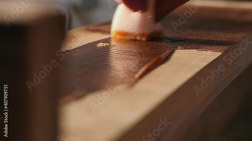 A joiner applies a wood impregnation to a wood product. a man covers a wooden shelf with oil for wood