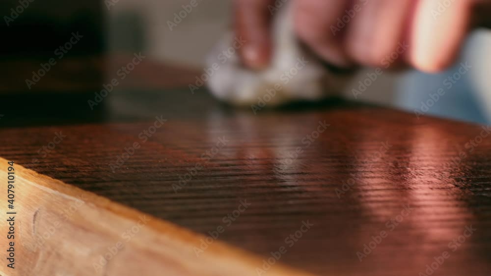 A joiner applies a wood impregnation to a wood product. a man covers a wooden shelf with oil for wood A joiner applies a wood impregnation to a wood product. a man covers a wooden shelf with oil for wood