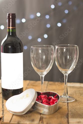 Image of Valentine's day, symbols of love, bottle and glasses of wine, sweets on a background of wooden boards.