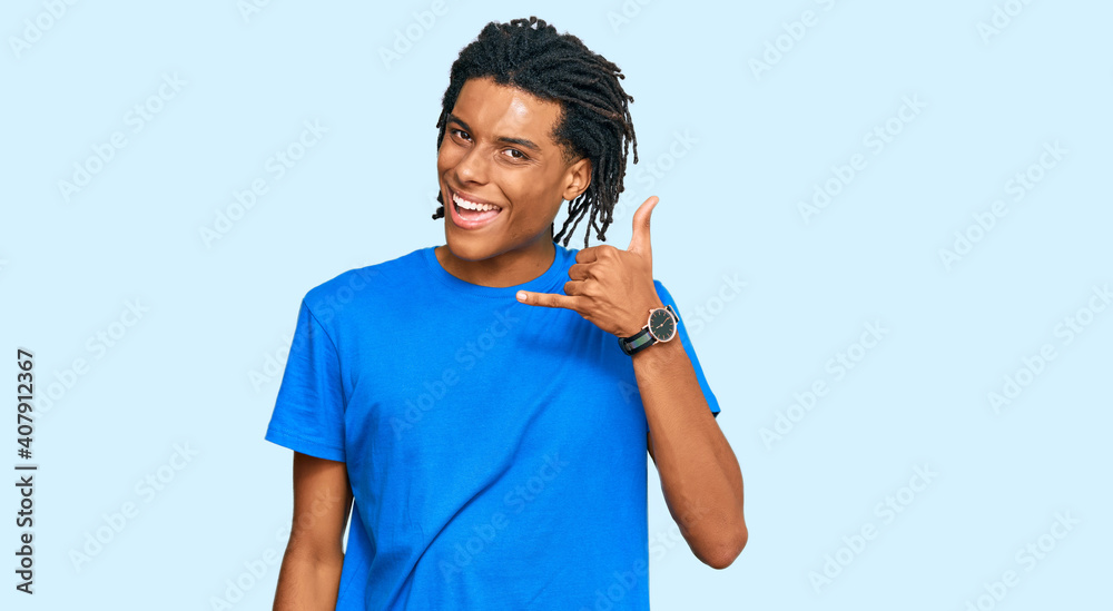 Young african american man wearing casual clothes smiling doing phone gesture with hand and fingers like talking on the telephone. communicating concepts. Young african american man wearing casual clothes smiling doing phone gesture with hand and fingers like talking on the telephone. communicating concepts.