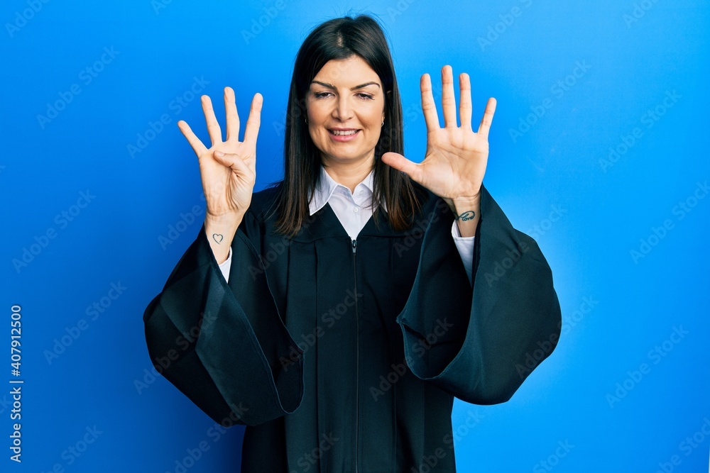 Young hispanic woman wearing judge uniform showing and pointing up with fingers number nine while smiling confident and happy.