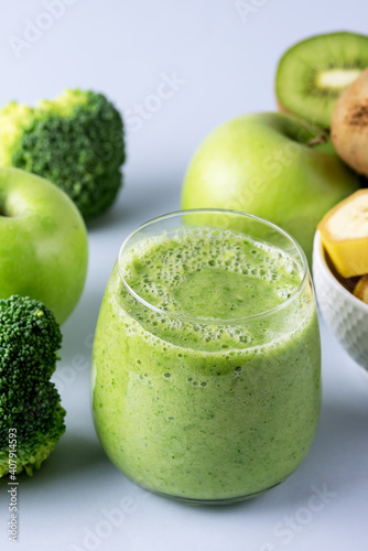 Glass of Fresh Green Smoothie with Kiwi Broccoli Green Apples and Babanas Healthy Detox Drink Blue Background photo