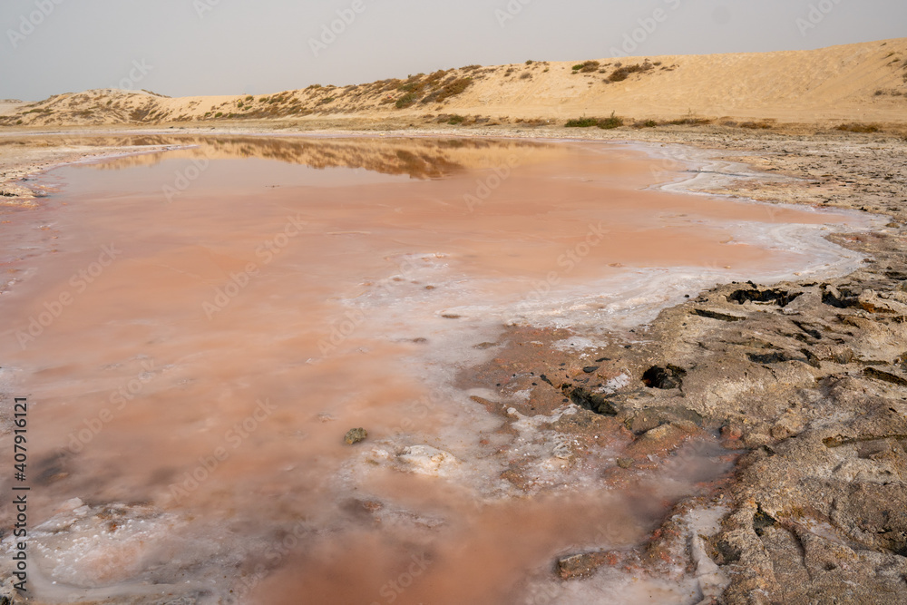 Pink lake and sand dunes view from water edge, from algae, salt, and minerals in Ras al Khaimah, United Arab Emirates. Pink lake and sand dunes view from water edge, from algae, salt, and minerals in Ras al Khaimah, United Arab Emirates.