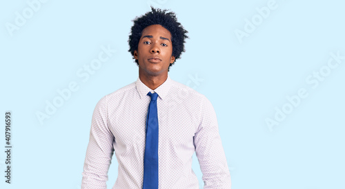 Handsome african american man with afro hair wearing business clothes with serious expression on face. simple and natural looking at the camera.