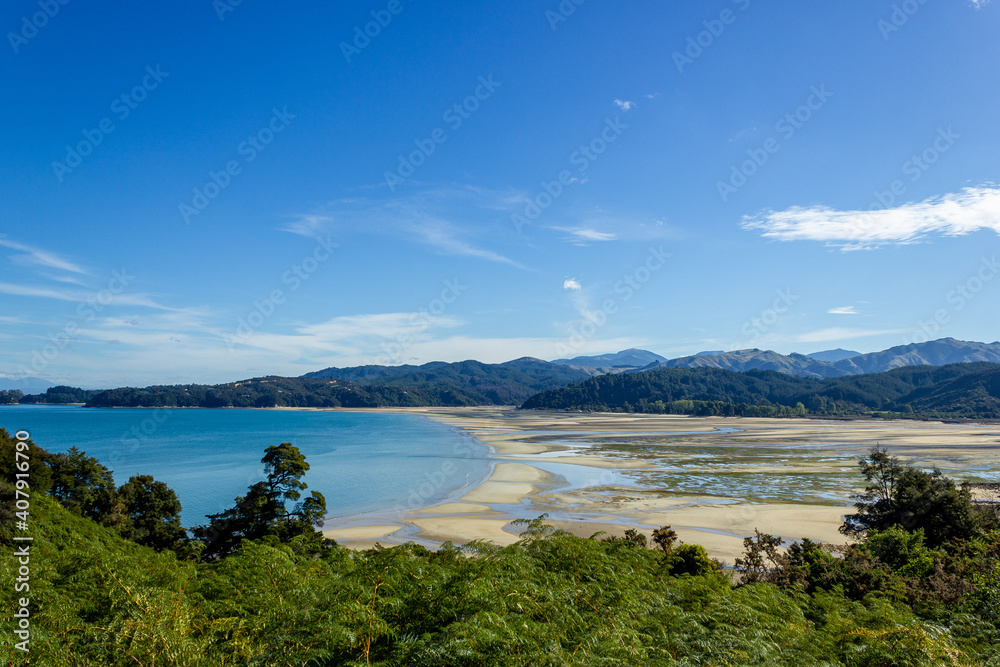 panoramic view of a tropical beach with turquoise water and white sand in abel tasman national park, new zealand