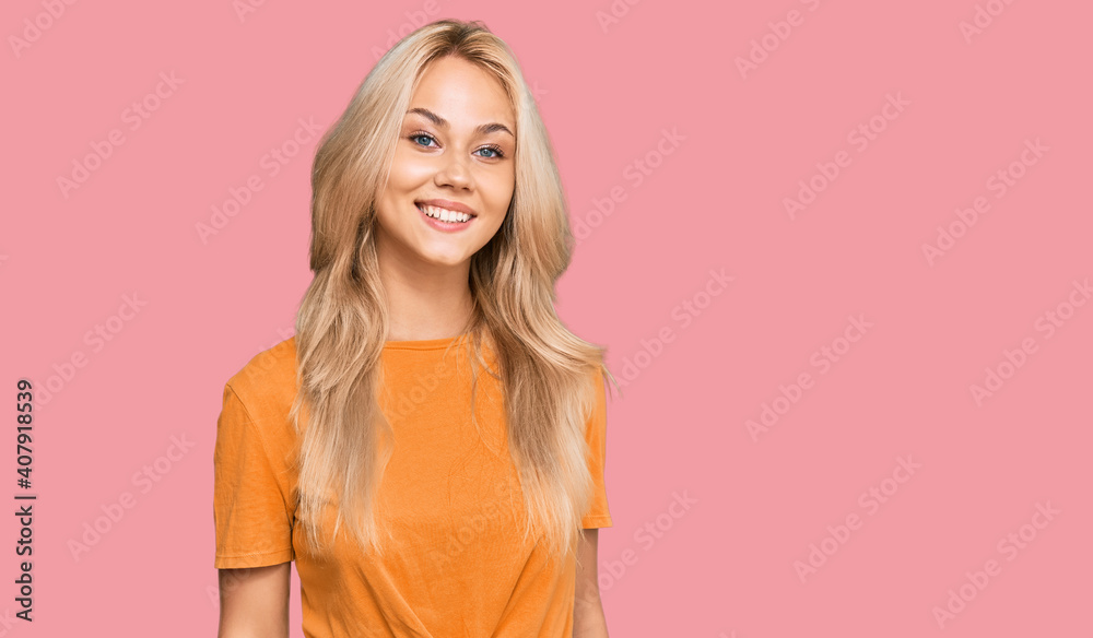 Young blonde girl wearing casual clothes looking positive and happy standing and smiling with a confident smile showing teeth Young blonde girl wearing casual clothes looking positive and happy standing and smiling with a confident smile showing teeth
