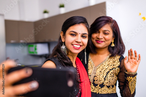 Photography two indian women in saree talk with family by phone video chatting at living roo