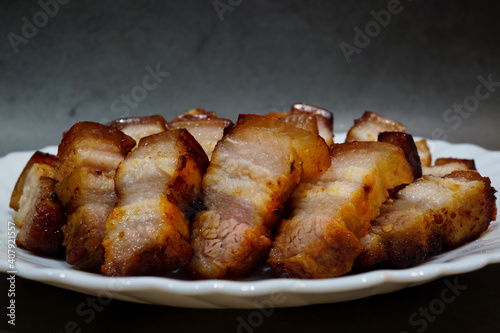 Salt and pepper, and Gochujang Korean sauce grilled pork belly on a white dish with a dark background