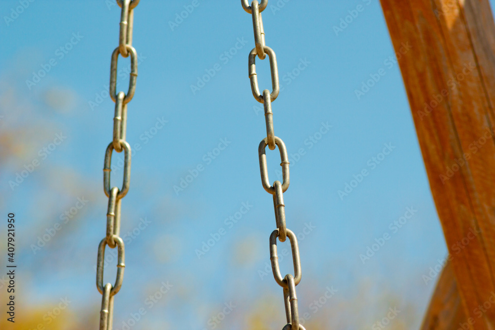 Metal chain from a swing in park on a background of blue day sky Metal chain from a swing in park on a background of blue day sky