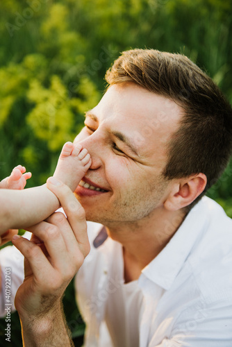 Young dad kisses the feet of a newborn close-up.