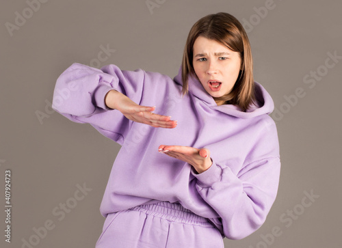 Portrait of a happy young woman doing throwing out money banknotes gesture isolated over gray background