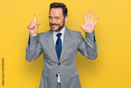Middle age man wearing business clothes showing and pointing up with fingers number seven while smiling confident and happy.