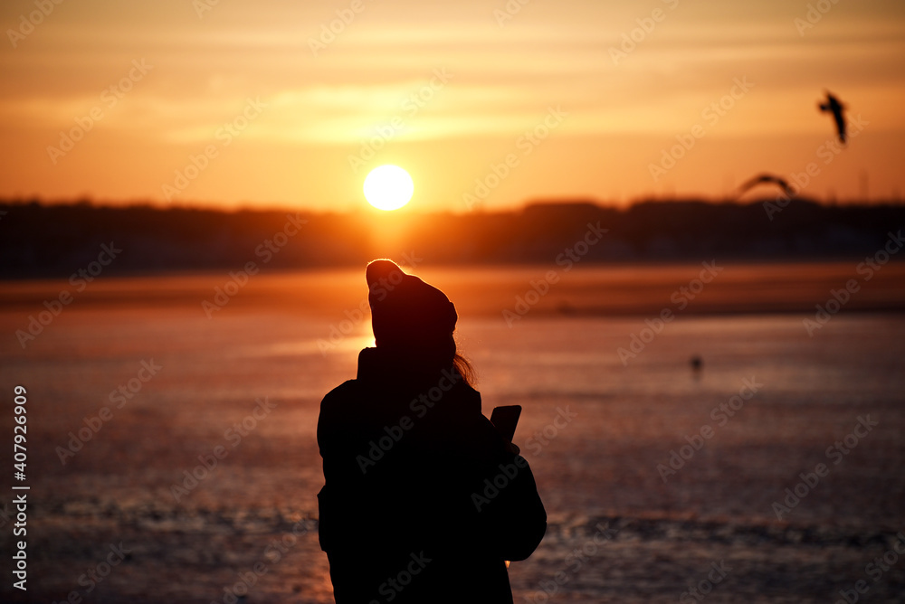 Silhouette of girl on sunset background making photo,winter