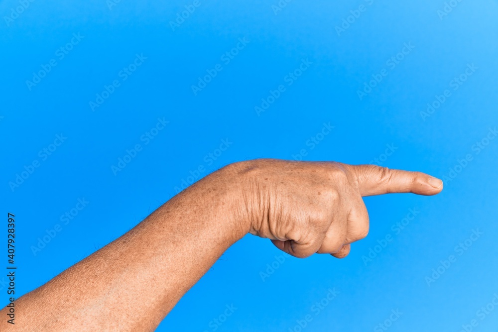 Hand of senior hispanic man over blue isolated background pointing with index finger to the side, suggesting and selecting a choice Hand of senior hispanic man over blue isolated background pointing with index finger to the side, suggesting and selecting a choice