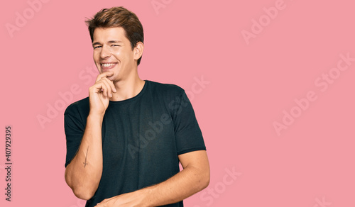 Handsome caucasian man wearing casual clothes looking confident at the camera with smile with crossed arms and hand raised on chin. thinking positive.