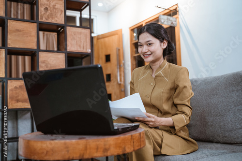 Foto woman in government uniform holding papers while working from home online using