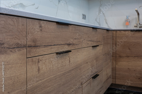 Lower kitchen cabinets with wood trim close-up with black metal handles.