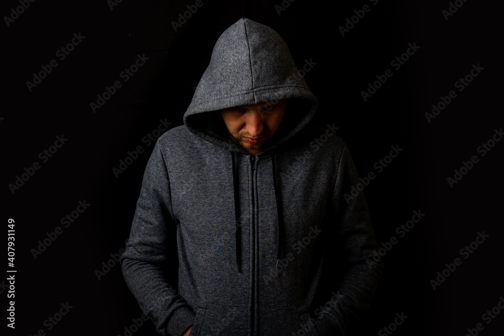 Man in a hood and a hoodie on a dark background
