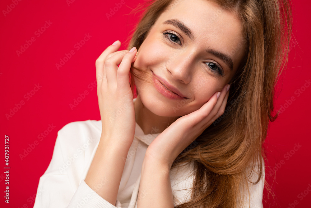 Young smiling sexy beautiful dark blonde woman with sincere emotions isolated on background wall with copy space wearing casual white hoodie. Positive concept