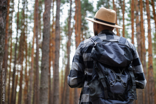 Young Man in a hat with a backpack in a pine forest. Hike in the mountains or forest