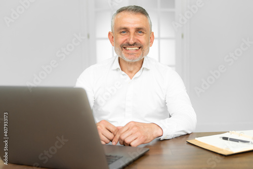 Portrait of young smiling cheerful businessman in office looking at camera