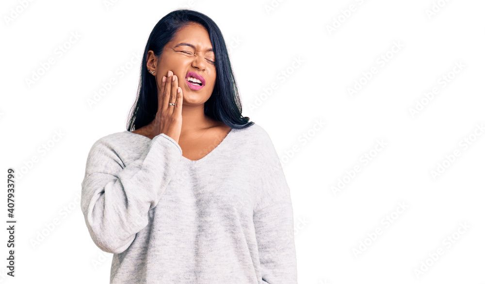 Hispanic woman with long hair wearing casual clothes touching mouth with hand with painful expression because of toothache or dental illness on teeth. dentist Hispanic woman with long hair wearing casual clothes touching mouth with hand with painful expression because of toothache or dental illness on teeth. dentist