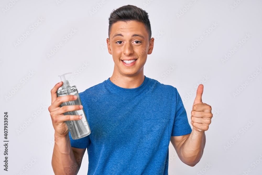 Young hispanic boy using hand sanitizer gel smiling happy and positive, thumb up doing excellent and approval sign Young hispanic boy using hand sanitizer gel smiling happy and positive, thumb up doing excellent and approval sign