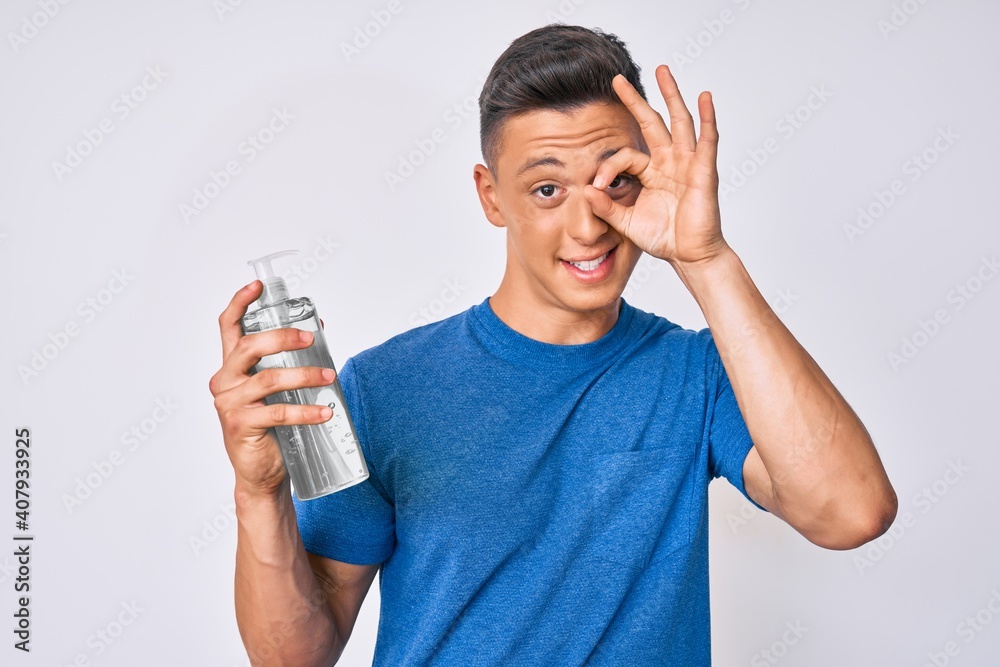 Young hispanic boy using hand sanitizer gel smiling happy doing ok sign with hand on eye looking through fingers Young hispanic boy using hand sanitizer gel smiling happy doing ok sign with hand on eye looking through fingers