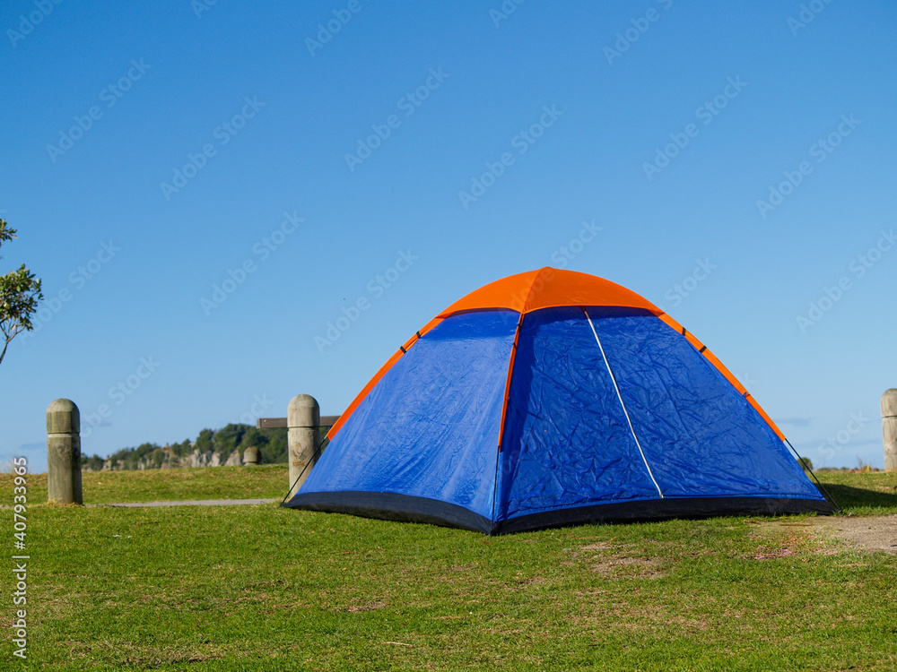 Blue tent with orange peak erected beside beach