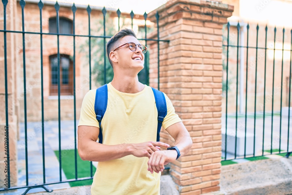 Young hispanic student smiling happy pointing with finger to the watch at street of city Young hispanic student smiling happy pointing with finger to the watch at street of city