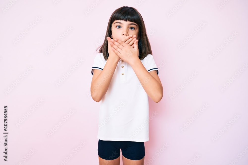 Young little girl with bang wearing sportswear shocked covering mouth with hands for mistake. secret concept. Young little girl with bang wearing sportswear shocked covering mouth with hands for mistake. secret concept.