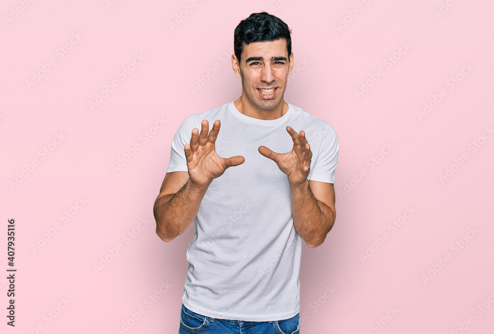 Handsome hispanic man wearing casual white t shirt disgusted expression, displeased and fearful doing disgust face because aversion reaction. with hands raised Handsome hispanic man wearing casual white t shirt disgusted expression, displeased and fearful doing disgust face because aversion reaction. with hands raised