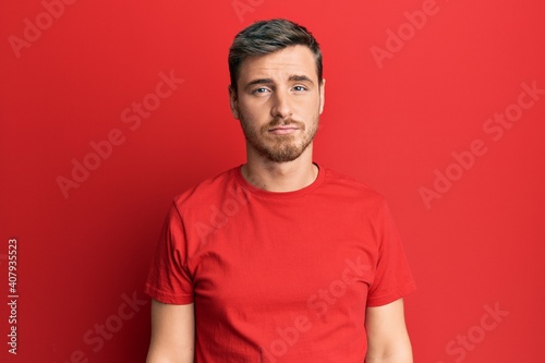 Handsome caucasian man wearing casual red tshirt depressed and worry for distress, crying angry and afraid. sad expression.