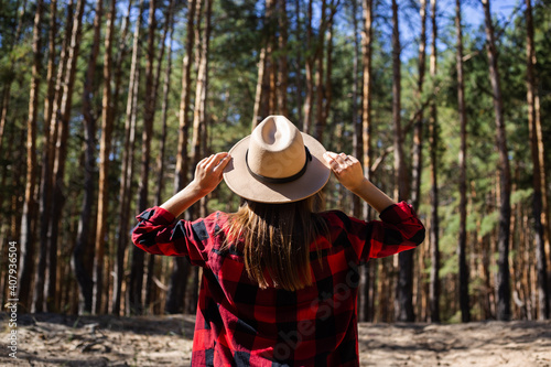 Woman with hat and red plaid shirt in the forest © Alex