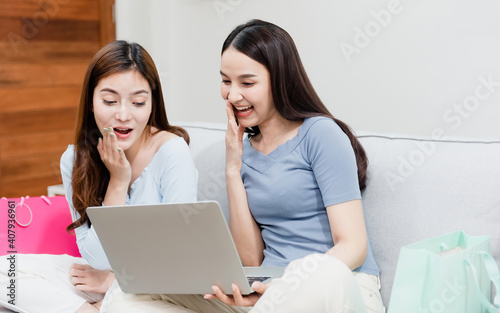 Two Asian beauty people are looking laptop. With a happy smiling face, being a new normal online business In the shopping experience from home © iSomboon