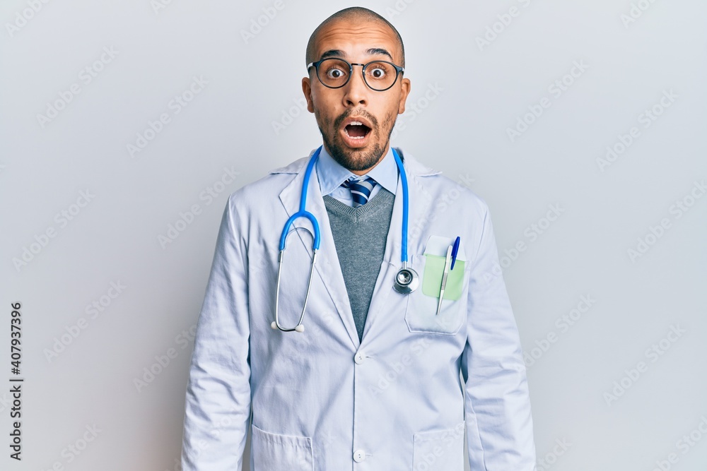 Hispanic adult man wearing doctor uniform and stethoscope afraid and shocked with surprise and amazed expression, fear and excited face. Hispanic adult man wearing doctor uniform and stethoscope afraid and shocked with surprise and amazed expression, fear and excited face.