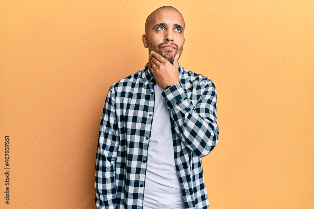 Fototapeta premium Hispanic adult man wearing casual clothes thinking concentrated about doubt with finger on chin and looking up wondering
