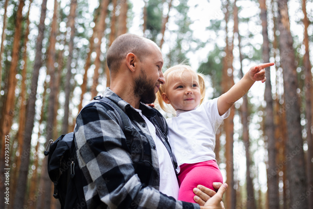Obraz premium Dad holds the baby in his arms while hiking in the woods. Family hike to the mountains or forest