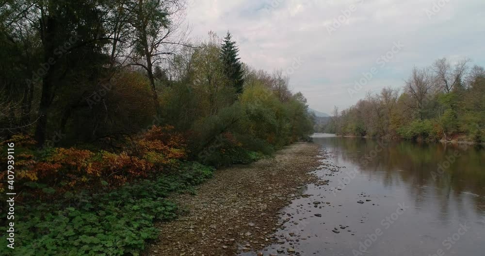 Drone flying over pristine Sava river in Slovenia. Forest covering river bank. Calm water flowing in Alpine valley. Beautiful nature with Alps mountains in the distance. Descending Drone flying over pristine Sava river in Slovenia. Forest covering river bank. Calm water flowing in Alpine valley. Beautiful nature with Alps mountains in the distance. Descending