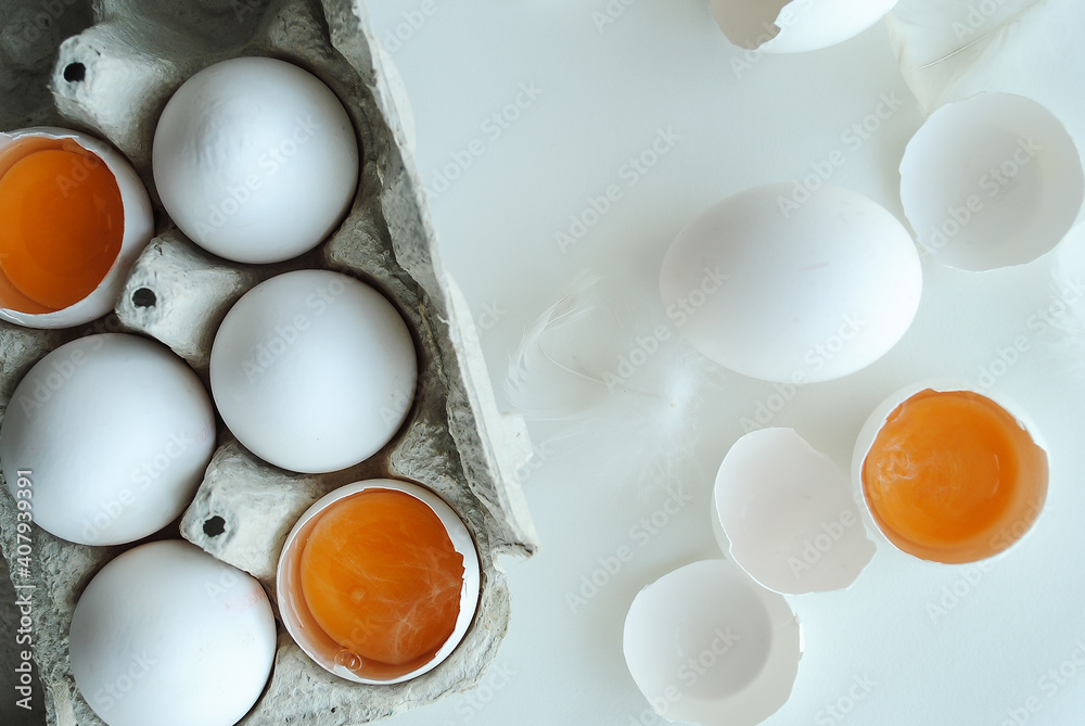 Chicken eggs in a tray on a white background, broken egg, white and yolk. Chicken eggs in a tray on a white background, broken egg, white and yolk.