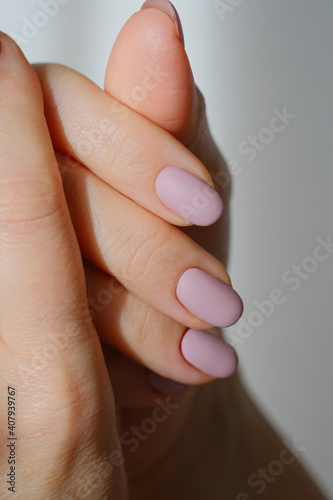 Female hands with new manicure in sunbeams on a blurred light background. Selective focus