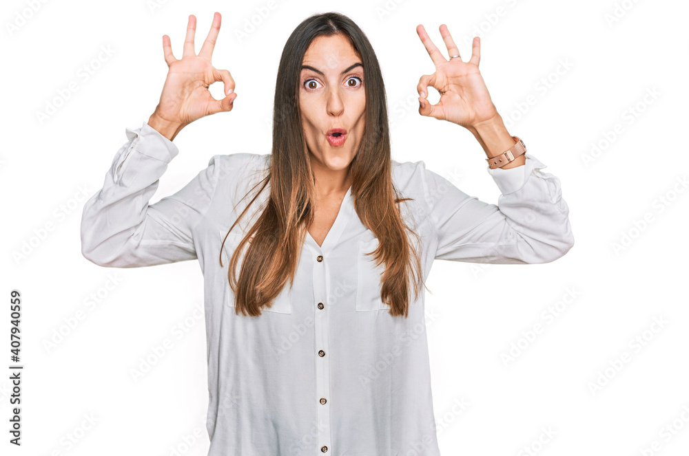 Young beautiful woman wearing casual clothes looking surprised and shocked doing ok approval symbol with fingers. crazy expression Young beautiful woman wearing casual clothes looking surprised and shocked doing ok approval symbol with fingers. crazy expression