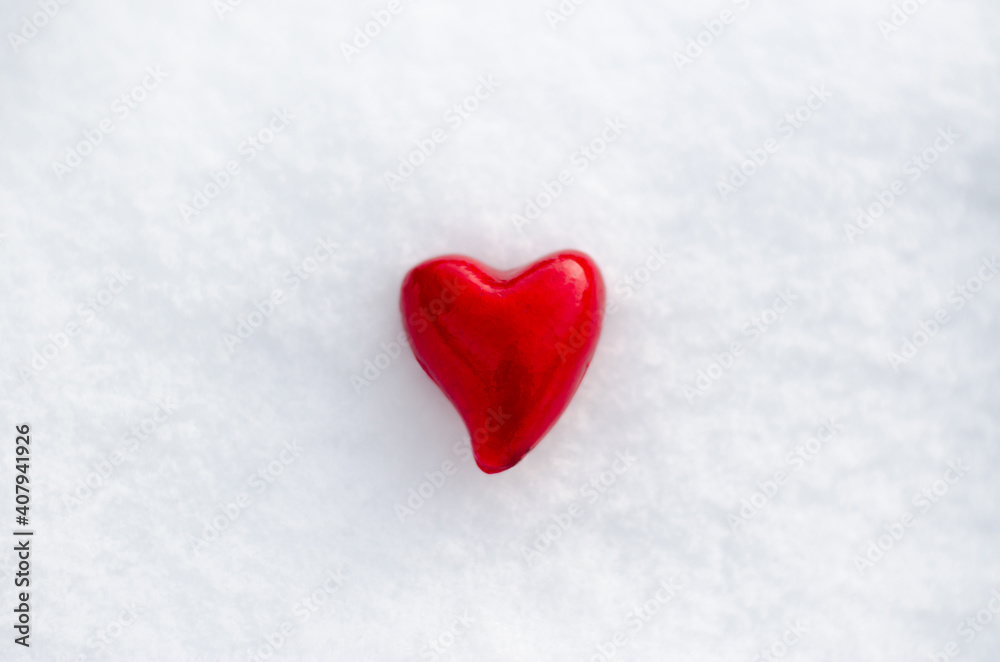 A red heart lies in the snow. Valentine's day background with place for text