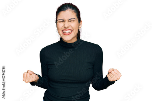 Young hispanic woman wearing casual clothes very happy and excited doing winner gesture with arms raised, smiling and screaming for success. celebration concept.