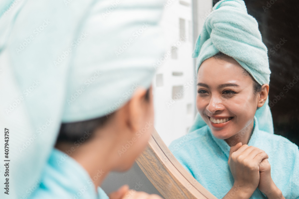 Close up of asian woman looking on reflection in the mirror after shower at the bathroom Close up of asian woman looking on reflection in the mirror after shower at the bathroom