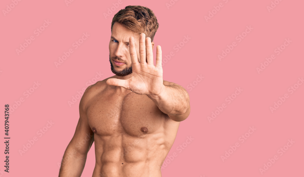 Fototapeta premium Young caucasian man standing shirtless doing stop sing with palm of the hand. warning expression with negative and serious gesture on the face.