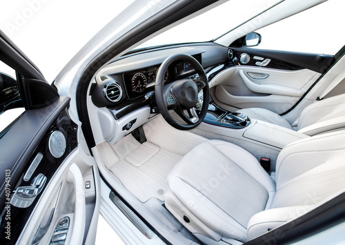 The car is inside. The interior of a prestigious modern car. Front seats with steering wheel, dashboard and display. white leather interior with black dashboard. on white background