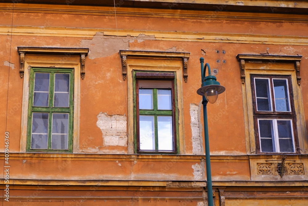 Old weathered orange brown colour vintage building detail with windows and a traditional metal street lamp in fornt of the house in Budapest downtown, Hungary